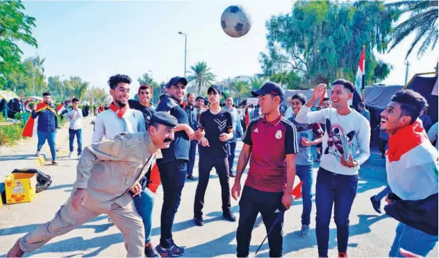  ?? Agence France-presse ?? ↑
A member of the Iraqi security forces plays football with young protesters during anti-government protests in Najaf on Tuesday.