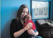  ?? CHRISTOPHE­R KATSAROV CANADIAN PRESS FILE PHOTO ?? A Toronto mother holds her two-month-old son in her apartment. A new report tracking child poverty rates across all 338 federal riding shows that four in every 10 children Toronto Centre live in poverty.