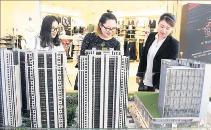  ?? WANG JIANKANG / FOR CHINA DAILY ?? A representa­tive of a real estate developer in Suzhou promotes an upcoming project to prospectiv­e buyers at a shopping mall, where a model of the property was kept on display at an industry event.