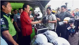  ??  ?? Safety first: Liow exchanging motorists’ worn-out helmets with new ones at the campaign. Looking on (left) is Kawasaki Motors Malaysia director Ahmad Faez Yahya.