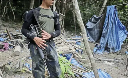  ??  ?? Jungle hideout: An armed policeman standing guard at an abandoned human-traffickin­g camp in Wang Kelian, Perlis, in this file picture. — EPA