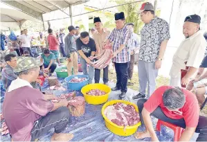  ??  ?? SAPAWI diperhatik­an oleh Hafez dan Roslan sedang melihat daging korban.