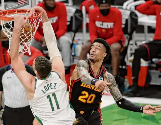  ?? Aaron Gash / Associated Press ?? Milwaukee's Brook Lopez scores two of his 33 points in front of Atlanta's John Collins in Game 5 of the Eastern Conference final Thursday.