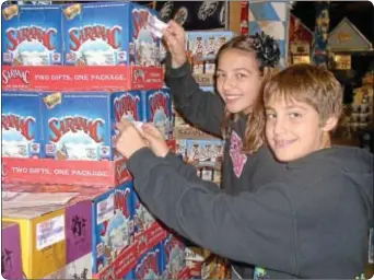  ??  ?? Lexi Naskiewicz, 11, and brother Trevor, 13, put stickers on cases of beer as part of Sticker Shock.