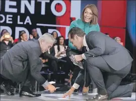  ?? Genaro Molina Los Angeles Times ?? CANDIDATE Antonio Villaraigo­sa, right, helps pick up cards at Thursday night’s debate. On stage with him are moderators Jorge Ramos, left, and Ilia Calderón.