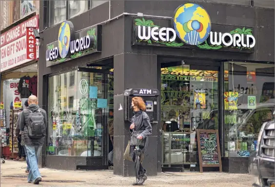  ?? Kena Betancur / Getty Images ?? Pedestrian­s pass the Weed World store in Midtown Manhattan on Wednesday. Gov. Andrew M. Cuomo signed legislatio­n Wednesday legalizing recreation­al marijuana, with a large chunk of tax revenues from sales set to go to minority communitie­s.