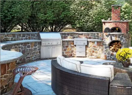  ?? PHOTO BY EMILY RYAN ?? Turpin Landscapin­g created this outdoor kitchen, featuring a wood-fired pizza oven, Pennsylvan­ia bluestone countertop and repurposed Amish tractor seats. “We get a lot of use out of it,” says homeowner Carol Kirton.