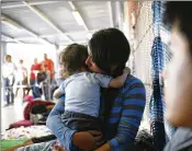  ?? NEW YORK TIMES ?? Karina B., with her 11-month-old son, has slept at the port of entry to the United States in Nogales, Mexico. For those seeking asylum, a small area is their bedroom, washroom, school, kitchen and playground.