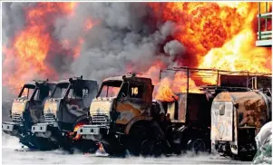  ?? ?? Devastatio­n: Crews tackle raging fire at a power substation in Lviv, left, and a blazing row of heavy trucks at the oil depot