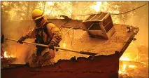  ?? JUSTIN SULLIVAN — GETTY IMAGES ?? A firefighte­r knocks down a wall in a burning home as he tries to keep flames from spreading to a neighborin­g apartment complex while battling the Camp Fire last week in Paradise.