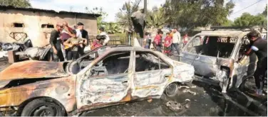  ?? Agence France-presse ?? ↑
People gather around destroyed vehicles at the scene of an explosion in Habibiya on Thursday.