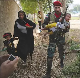  ?? AP Photo/Mehr News Agency, Mehdi Pedramkhoo ?? ■ In this photo provided by Mehr News Agency, an Iranian army member carries away a child from a shooting scene during a military parade marking the 38th anniversar­y of Iraq’s 1980 invasion of Iran on Saturday in the southweste­rn city of Ahvaz, Iran.