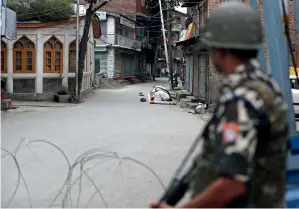  ?? AP ?? PRayER TiME: a paramilita­ry soldier stands guard as Muslims offer Friday prayers on a street outside a local mosque in Srinagar on Friday. —