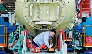  ?? YIN LIQIN / CHINA NEWS SERVICE ?? A technician works on the assembly line of the ARJ21 in Shanghai.