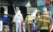  ?? YONHAP VIA REUTERS ?? Firefighte­rs and rescue workers check the condition of survivors rescued from an under-constructi­on warehouse after it caught fire in Icheon, South Korea, on Wednesday. At least 25 people were killed in the incident.