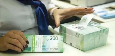  ?? R euters ?? ±
A cashier holds new 200 rouble banknotes in a bank in Moscow, Russia.