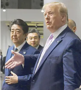  ??  ?? US President Donald Trump, walking with Japanese Prime Minister Shinzo Abe, stops to ask a question after he arrived at the G20 summit in Osaka, Japan on Friday.