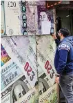  ?? Reuters ?? A man takes a photograph of exchange rates in front of an exchange point, displaying images of different currencies, in Cairo. —