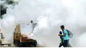  ??  ?? Children walk through the smoke as a Corporatio­n worker fogs in the view of spread of dengue, in Chennai on Friday