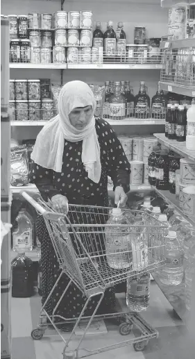  ?? JOSEPH EID / AFP / GETTY IMAGES ?? A Syrian refugee does some grocery shopping in Beirut last month at a store that accepts the United Nations’ World Food Program electronic cards.