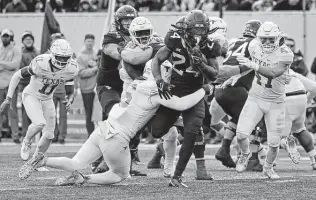  ?? Kathleen Batten / Associated Press ?? Texas linebacker Ben Davis (6) grabs West Virginia running back Tony Mathis Jr. during the second half. The loss Saturday extended Texas’ skid to six and assured no bowl berth.