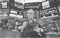  ?? RICHARD DREW, AP ?? Trader Eric Schumacher goes over the numbers on the floor of the New York Stock Exchange last Wednesday.