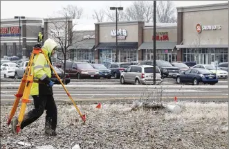  ?? TY GREENLEES / STAFF ?? Land surveyor William Mayes carries a tripod across a vacant lot for measuremen­ts near the Shoppes at Fairfield Commons. The business area around the mall continues to grow and Mayes is part of a survey crew preparing the site for constructi­on of a medical office.