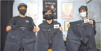 ??  ?? RDH founder Ahmad Safuan Nizam Kamaruddin (right) with his brother Ahmad Syukri, (center) and their friend Muhamad Aidil Akhyar showing the vintage concept jeans from their collection­s. - Bernama photo