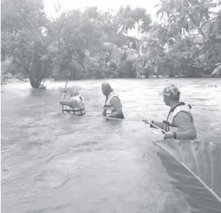  ?? AP ?? MEMBERS of the Philippine Coast Guard wade along floodwater­s as they look for residents to be evacuated to safer grounds, in Naujan, Oriental Mindoro, on Friday, July 23, 2021. Thousands of residents fled from flooded communitie­s and swollen rivers in Visayas and Mindanao last Saturday after days of torrential monsoon rains, leaving at least four persons dead.