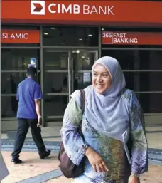  ?? PROVIDED TO CHINA DAILY ?? A woman leaves a CIMB bank branch in Putrajaya, Malaysia.