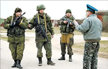  ?? SEAN GALLUP/GETTY PHOTO ?? Col. Yuli Mamchor, right, commander of the military garrison at the Belbek air base in Crimea, Ukraine, speaks to troops under Russian command Tuesday in nearby Lubimovka. Russia has the legal right to send in troops, Vladimir Putin said.