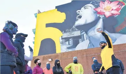  ?? AMY DAVIS/BALTIMORE SUN ?? Rob Jackson, right, founder of the running group RIOT (Running Is Our Therapy) Squad shares Black history at Penn North, in front of a Billie Holiday mural at the Arch Social Club, during a Sunday run. The RIOT Squad has incorporat­ed Black history in its February runs.