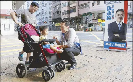  ?? REUTERS ?? Steve Ng Wing- tat, a former chef who participat­ed in Occupy Central protests in 2014 and is running for the upcoming district elections, chats with a passerby and a baby during a campaign in Hong Kong Saturday.