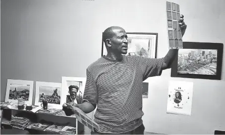  ?? Picture: Lucas Ledwaba/Mukurukuru Media ?? HISTORY, CAPTURED Bongani Mnguni studies images at his studio in Roodepoort, Johannesbu­rg.