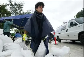  ?? WILFREDO LEE — THE ASSOCIATED PRESS ?? City worker Enrique Pulley prepares to load sandbags at a drive-thru sandbag distributi­on event for residents ahead of the arrival of rains associated with tropical depression Fred Aug. 13at Grapeland Park in Miami.