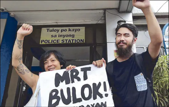  ?? MICHAEL VARCAS ?? Commuters’ rights activist Angelo Suarez and his partner, Donna Miranda, hold a placard following his release from the Kamuning, Quezon City police station yesterday. He was arrested by Metro Rail Transit security personnel Tuesday night for reportedly...