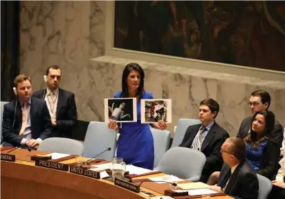  ?? (Shannon Stapleton/Reuters) ?? US AMBASSADOR Nikki Haley displays photograph­s of victims of chemical weapons during a meeting yesterday of the UN Security Council, where she lambasted Moscow for aiding and abetting the Assad regime.