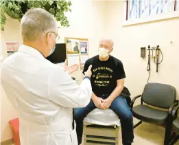  ?? JEFFREY F. BILL/CAPITAL GAZETTE ?? During a follow-up appointmen­t at Luminis Health Anne Arundel Medical Center, Dr. Angel E. Torano, radiation oncologist, discusses with Mulligan how staying active during radiation treatment for his reoccurrin­g sarcoma and the reoccurrin­g prostate cancer played an important role in his recovery.