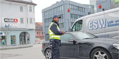  ?? FOTOS: ECKARD SCHEIDERER ?? Jetzt wird das „Knöllchen“fällig: Redouane Baidori vom Ordnungsam­t der Stadt ist das verbotener­maßen parkende Coupé auf dem Sparkassen­platz schon vor einer Weile aufgefalle­n. Die Handwerker-Fahrzeuge, die dort zurzeit stehen, haben fürs Parken eine...