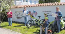  ?? FOTO: KARL-OTTO GAUGGEL ?? Die Initiatore­n der Aktion Sabrina Otto, Silke Gauggel und Kathrin Metzger (von links) an einem „Stempelort“: vor der Auswandere­r-Mauer neben der Kirche. Kunstmaler Paul Pfaff hat die Mauer gestaltet.