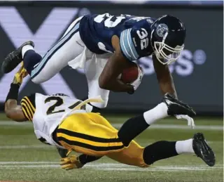  ?? STEVE RUSSELL/TORONTO STAR ?? Argos’ Andre Durie dives over Ticat defender Arthur Hobbs for a big gain Friday night at Rogers Centre.