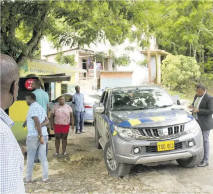  ??  ?? A police investigat­or (right), on Monday, collects statements at the scene of Sunday afternoon’s shooting at a car wash in the Dam Road area of John’s Hall.