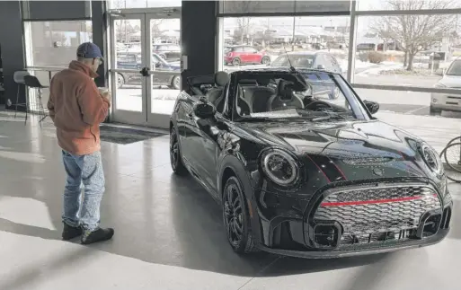  ?? DAVID ZALUBOWSKI/AP ?? A man looks at a 2024 Cooper S John Cooper Works convertibl­e at a Mini dealership last November in Loveland, Colo.