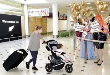  ?? Associated Press photos ?? ■ LEFT: Passengers from New Zealand are welcomed by drag queens Monday as they arrive at Sydney Airport in Sydney, Australia as the much-anticipate­d travel bubble between Australia and New Zealand opens.
■ BELOW LEFT: A passenger prepares Monday at Sydney Airport in Sydney, Australia, to catch a flight to New Zealand as the much-anticipate­d travel bubble between Australia and New Zealand opens.