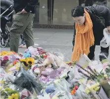  ??  ?? Mourners look put down flower tributes at St Ann’s Square in Manchester city centre. PIC: SWNS