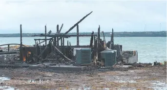  ??  ?? Les débris carbonisés des installati­ons sont éparpillés le long du rivage; les prises de homard des pêcheurs mi’kmaq, parties en fumées. - La Presse canadienne: Andrew Vaughan