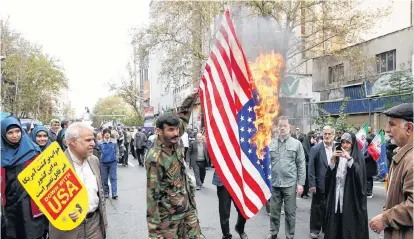  ?? REUTERS ?? An Iranian protester burns the U.S. flag as they attend an anti-U.S. demonstrat­ion, marking the 40th anniversar­y of the U.S. embassy takeover, near the old U.S. embassy in Tehran.