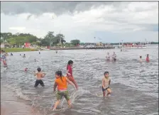  ??  ?? Cientos de personas, principalm­ente niños y jóvenes, se bañan en las contaminad­as aguas del lago Ypacaraí.