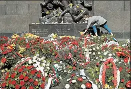  ?? SEAN GALLUP/GETTY ?? A woman lays daffodils Thursday at the Ghetto Heroes Monument after the main commemorat­ion ceremony of the 75th anniversar­y of the Warsaw Ghetto Uprising in Poland.