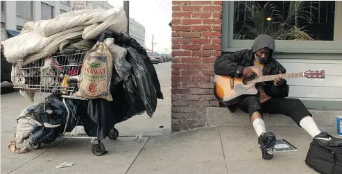  ?? JUSTIN SULLIVAN / GETTY IMAGES FILES ?? James Faulkner, a homeless man, plays his guitar near his shopping cart in the Mission District in San Francisco. Homelessne­ss is up in the city, partly due to rising rents and home prices as high-tech jobs proliferat­e.